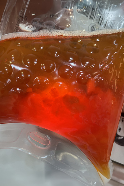 展示血液淨化過程中的廢液，顯示紅色液體和泡沫層，表現出淨化過程的成果。